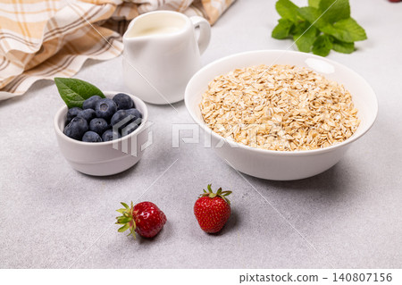 Healthy oatmeal breakfast preparation with fresh berries and milk 140807156