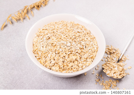 Dry rolled oats in bowl with spoon and stalks Dry rolled oats in bowl with spoon and stalks 140807161