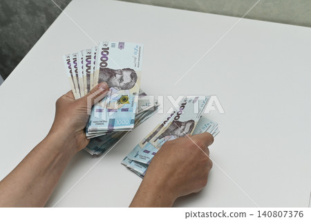 money in hands being sorted and counted on white table, money in hands being sorted and counted on white table, 140807376