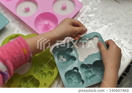 Kid removes plaster figure after removing it from soft blue tray. Kid removes plaster figure after removing it from soft blue tray. 140807468