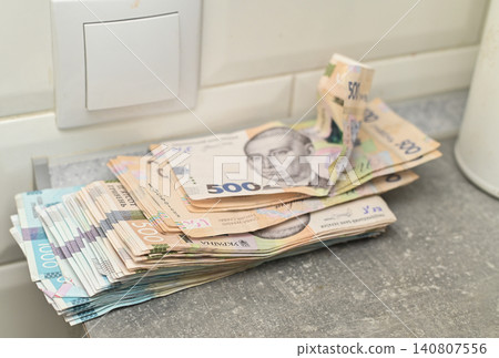 Many ukrainian hryvnia bills scattered on grey surface near light switch. Many ukrainian hryvnia bills scattered on grey surface near light switch. 140807556