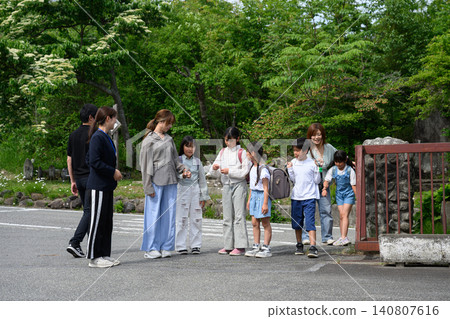 教師、家長和小學生在校門口排成一列,拍攝了一張團體照。 教師、家長和小學生在校門口排成一列,拍攝了一張團體照。 140807616