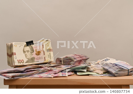 Ukrainian banknotes of different denominations stacked and spread on a table. 140807734
