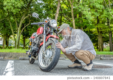 Senior riders inspect their motorcycles before a touring trip. Senior riders inspect their motorcycles before a touring trip. 140807841