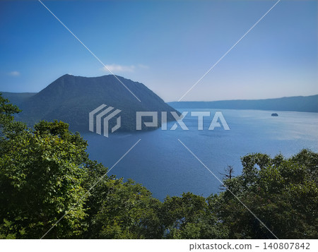 Summer Lake Mashu as seen from Ura-Mashu Observatory in Hokkaido at the end of July, with a spectacular view of Kamuy-shu Island seen through the trees. Summer Lake Mashu as seen from Ura-Mashu Observatory in Hokkaido at the end of July, with a spectacular view of Kamuy-shu Island seen through the trees. 140807842