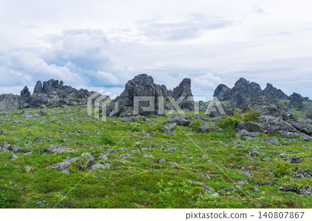 Mountain landscape with green grass and rocks under cloudy sky in summer 140807867