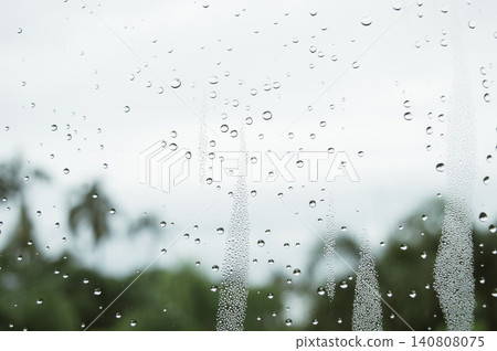 raindrops during raining in the rainy day outside window glass with a blurred background with water droplets flowing down the surface raindrops during raining in the rainy day outside window glass with a blurred background with water droplets flowing down the surface 140808075