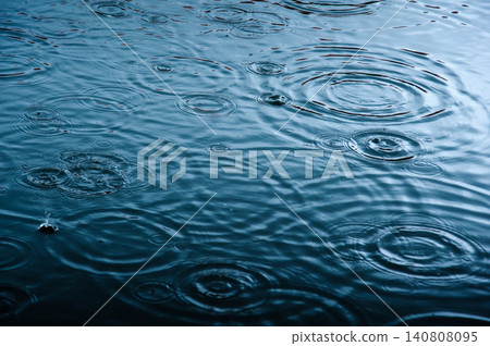 rain drops on the surface of water in a puddle with graduated shade of black shadow and reflection of blue sky rain drops on the surface of water in a puddle with graduated shade of black shadow and reflection of blue sky 140808095