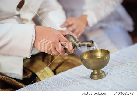 hands of the Bridge and groom holding together to pouring holy water to paying in Thai style traditional wedding ceremony. hands of the Bridge and groom holding together to pouring holy water to paying in Thai style traditional wedding ceremony. 140808178