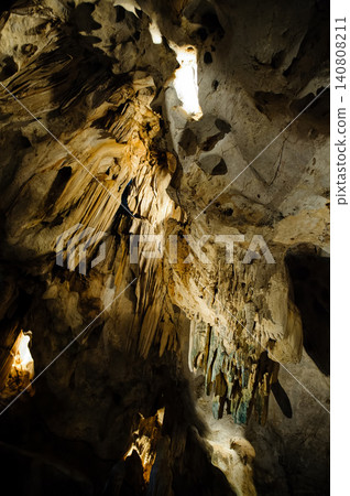 a cave with stalagmites and stalactites. The cave is large and dark, and the walls are covered in a variety of different rock formations. The stalagmites and stalactites are a variety of shapes and a cave with stalagmites and stalactites. The cave is large and dark, and the walls are covered in a variety of different rock formations. The stalagmites and stalactites are a variety of shapes and 140808211