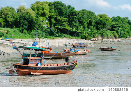 many empty Thai fishing boats lay down on a sea base next to the beach that run out of seawater during low tide many empty Thai fishing boats lay down on a sea base next to the beach that run out of seawater during low tide 140808256
