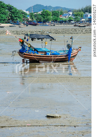 many empty Thai fishing boats lay down on a sea base next to the beach that run out of seawater during low tide many empty Thai fishing boats lay down on a sea base next to the beach that run out of seawater during low tide 140808257