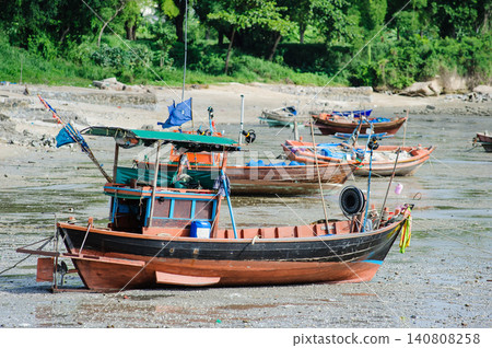 many empty Thai fishing boats lay down on a sea base next to the beach that run out of seawater during low tide 140808258
