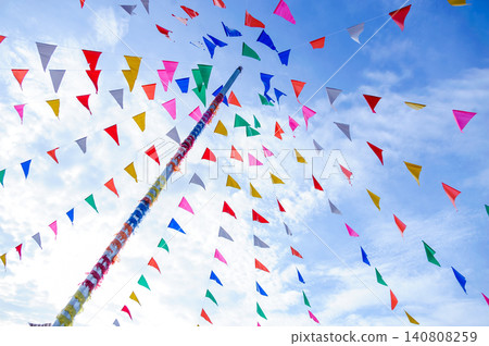 vivid color of Thai's style fancy party flag strips decoration on a fancy still pole with blue sky and white cloud in background vivid color of Thai's style fancy party flag strips decoration on a fancy still pole with blue sky and white cloud in background 140808259