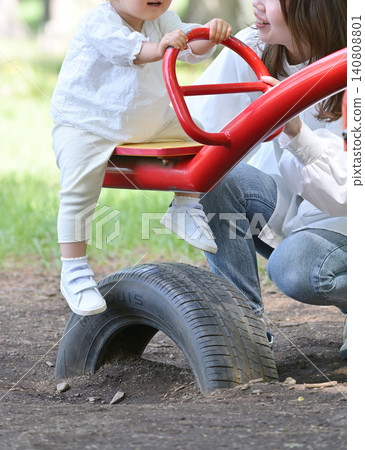 A mother and daughter enjoying a seesaw in the park. A mother and daughter enjoying a seesaw in the park. 140808801