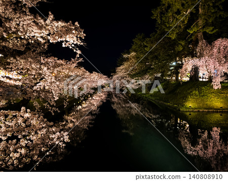 四月盛開的櫻花倒映在弘前公園的外護城河。夜晚，美麗的櫻花燈光灑滿水面。 [夜景版] 140808910