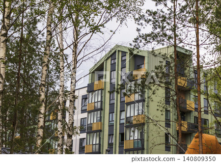 Contemporary olive green apartment building with modern balconies framed by birch and pine trees in an eco-friendly neighborhood. Contemporary olive green apartment building with modern balconies framed by birch and pine trees in an eco-friendly neighborhood. 140809350