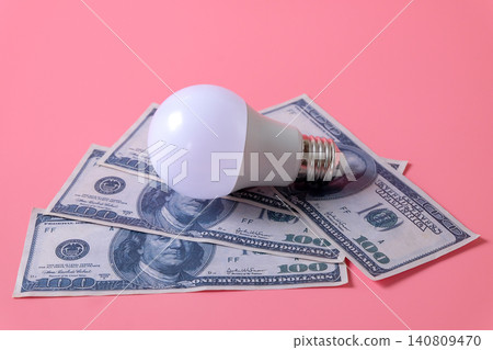 Light bulb on 100 US. currency banknotes over color background. Light bulb on 100 US. currency banknotes over color background. 140809470