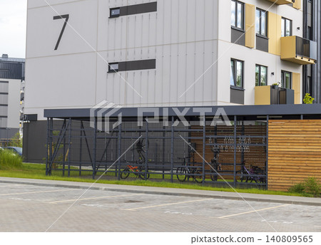 Modern secure bicycle storage locker and outdoor parking zone next to a contemporary residential apartment building. 140809565