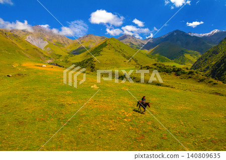 Cowboy on Horseback Riding in Kyrgyz Mountain Meadow Cowboy on Horseback Riding in Kyrgyz Mountain Meadow 140809635