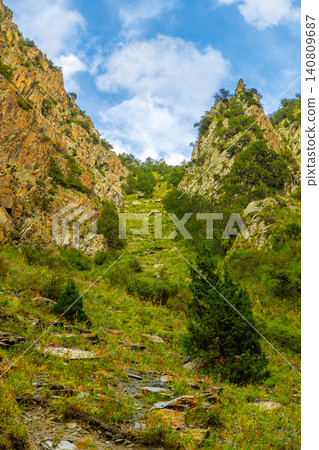 Lush green mountain slope with rocky terrain in Kyrgyzstan Lush green mountain slope with rocky terrain in Kyrgyzstan 140809687