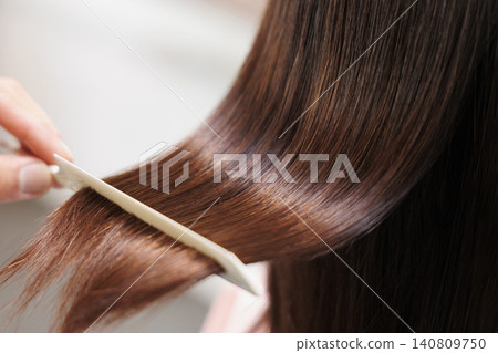 Combing a woman's glossy, long brown hair. Combing a woman's glossy, long brown hair. 140809750