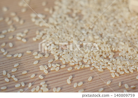 Close-up of brown rice grains scattered on a wooden table Close-up of brown rice grains scattered on a wooden table 140809759