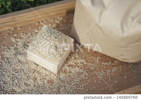 量杯和布米袋裡裝著糙米；散落的米粒。 140809760
