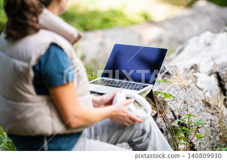 Woman with laptop and wireless headphones working in a peaceful forest Woman with laptop and wireless headphones working in a peaceful forest 140809930