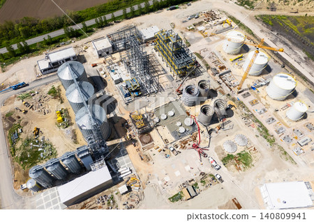 Construction site of a modern agricultural complex with silos, grain elevator and storage terminal. Aerial view. Construction site of a modern agricultural complex with silos, grain elevator and storage terminal. Aerial view. 140809941