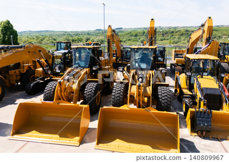 New hydraulic excavators and tractors parked at a construction machinery dealership. 140809967