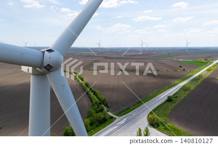 Close-up of a wind turbine with a wind farm on the horizon 140810127