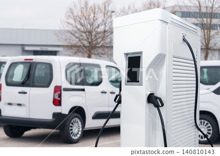 Electric vehicles charging station on a background of a row of vans. Green transportation concept. Electric vehicles charging station on a background of a row of vans. Green transportation concept. 140810143