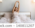 Happy black woman is stretching in bed after waking up 140811207