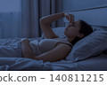 Black woman lying awake in bed at night pinching nose, suggesting sinus 140811215
