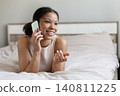 Happy black woman lying on bed while talking on smartphone 140811225