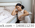 Sad black woman sitting on bedroom floor beside an unmade bed 140811230