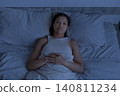 Black woman lying awake in bed at night with serious expression 140811234