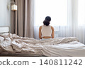 Rear view of black woman sitting on edge of bed in bedroom 140811242