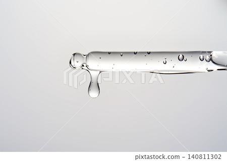 Clear serum droplet dripping from cosmetic pipette Clear serum droplet dripping from cosmetic pipette 140811302