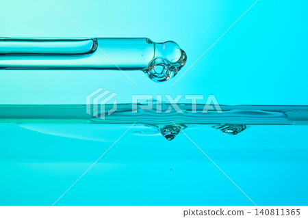 Dropper dispensing blue liquid into water surface Dropper dispensing blue liquid into water surface 140811365