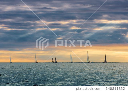 A lot of sailing boats are in sailing regatta in the Gulf of Finland at sunset, Russia, St.Petersburg, hot race of several yachts, teamwork, yachtsman 140811832
