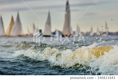 A lot of sailing boats through splashing water at sunset, Sailing regatta in the Gulf of Finland at sunset, hot race of several yachts, teamwork 140811843