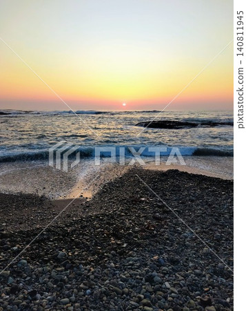 A beautiful sunrise rising from the horizon and the scenery of waves crashing against the shore. A beautiful sunrise rising from the horizon and the scenery of waves crashing against the shore. 140811945