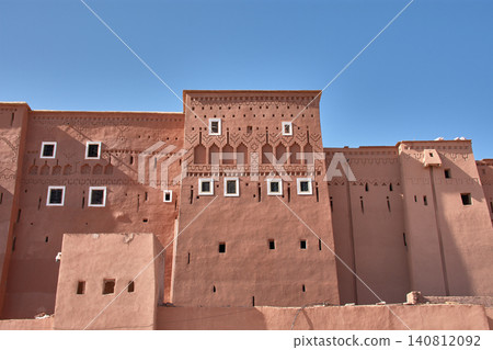The ancient adobe walls of the Kasbah of Taourirt display their typical reliefs in Ouarzazate, Morocco. The ancient adobe walls of the Kasbah of Taourirt display their typical reliefs in Ouarzazate, Morocco. 140812092
