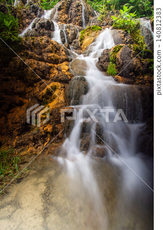 Beautiful silk effect waterfall flowing down mossy rock cliffs at Goa Tetes Lumajang Indonesia Beautiful silk effect waterfall flowing down mossy rock cliffs at Goa Tetes Lumajang Indonesia 140812383