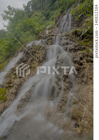 Beautiful silk effect waterfall flowing down mossy rock cliffs at Goa Tetes Lumajang Indonesia Beautiful silk effect waterfall flowing down mossy rock cliffs at Goa Tetes Lumajang Indonesia 140812384
