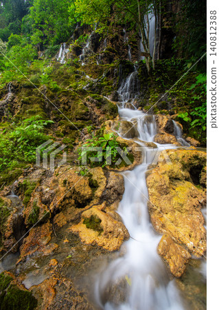 Beautiful silk effect waterfall flowing down mossy rock cliffs at Goa Tetes Lumajang Indonesia 140812388