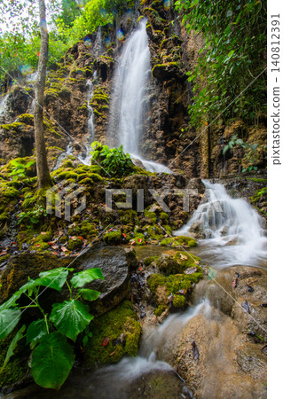 Beautiful silk effect waterfall flowing down mossy rock cliffs at Goa Tetes Lumajang Indonesia Beautiful silk effect waterfall flowing down mossy rock cliffs at Goa Tetes Lumajang Indonesia 140812391