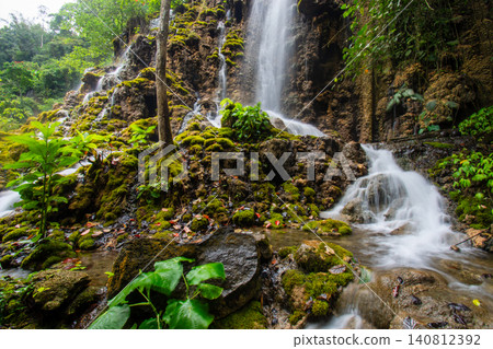Beautiful silk effect waterfall flowing down mossy rock cliffs at Goa Tetes Lumajang Indonesia Beautiful silk effect waterfall flowing down mossy rock cliffs at Goa Tetes Lumajang Indonesia 140812392